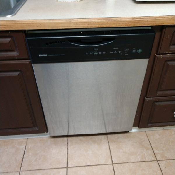 Dishwasher installed between two brown cabinets.